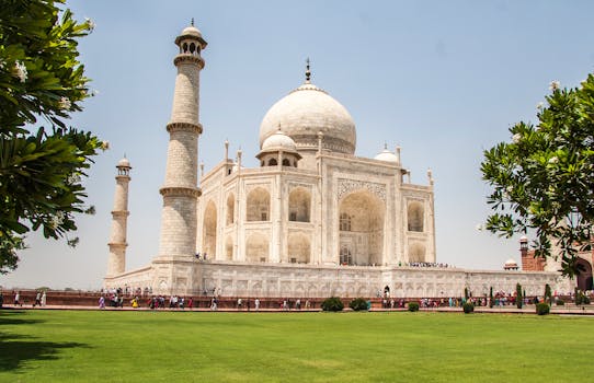 Iconic Taj Mahal showcasing its white marble beauty and lush gardens on a sunny day.