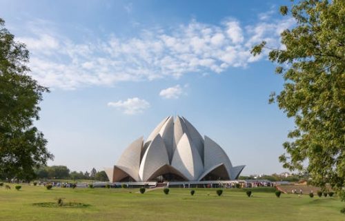 A stunning view of the Lotus Temple in Delhi, surrounded by greenery and clear skies.